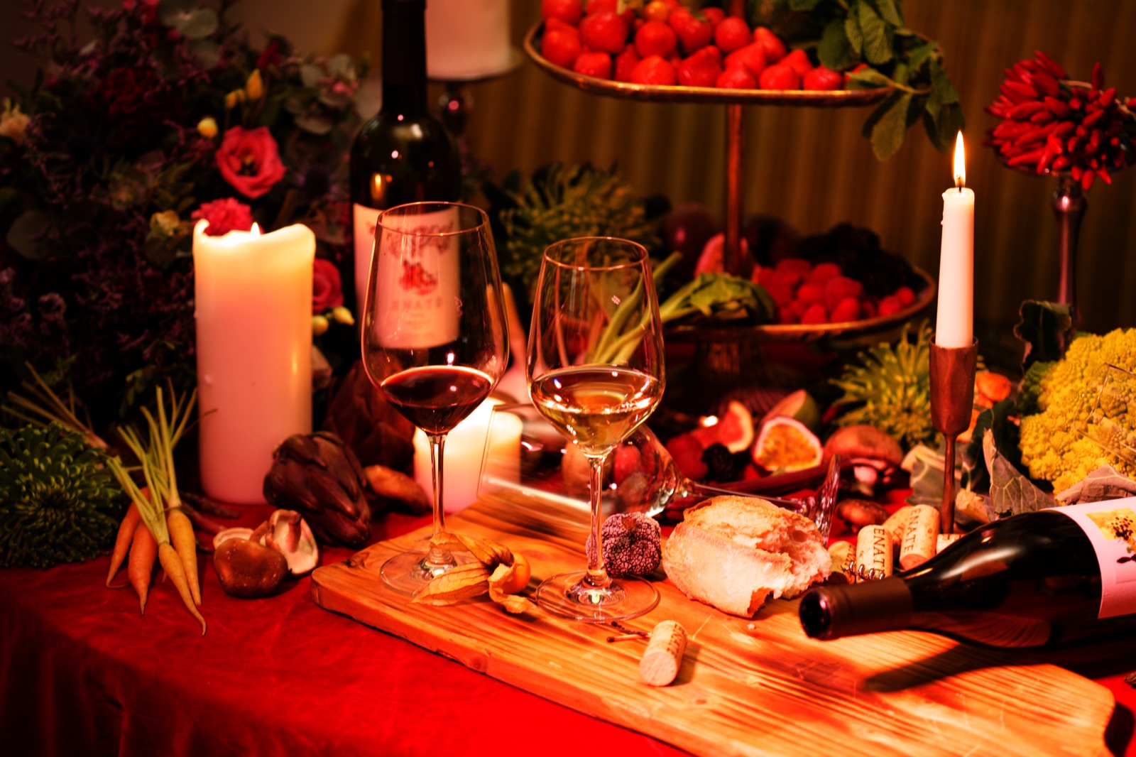 Weingläser, Kerzen, Obst und Gemüse auf einer dekorierten Tafel
