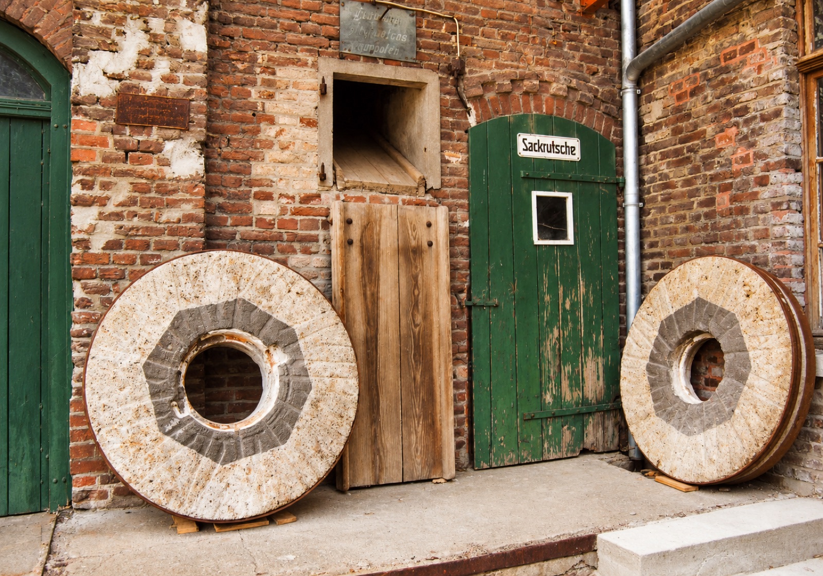Zwei historische Mühlsteine vor der Sackrutsche der Viller Mühle